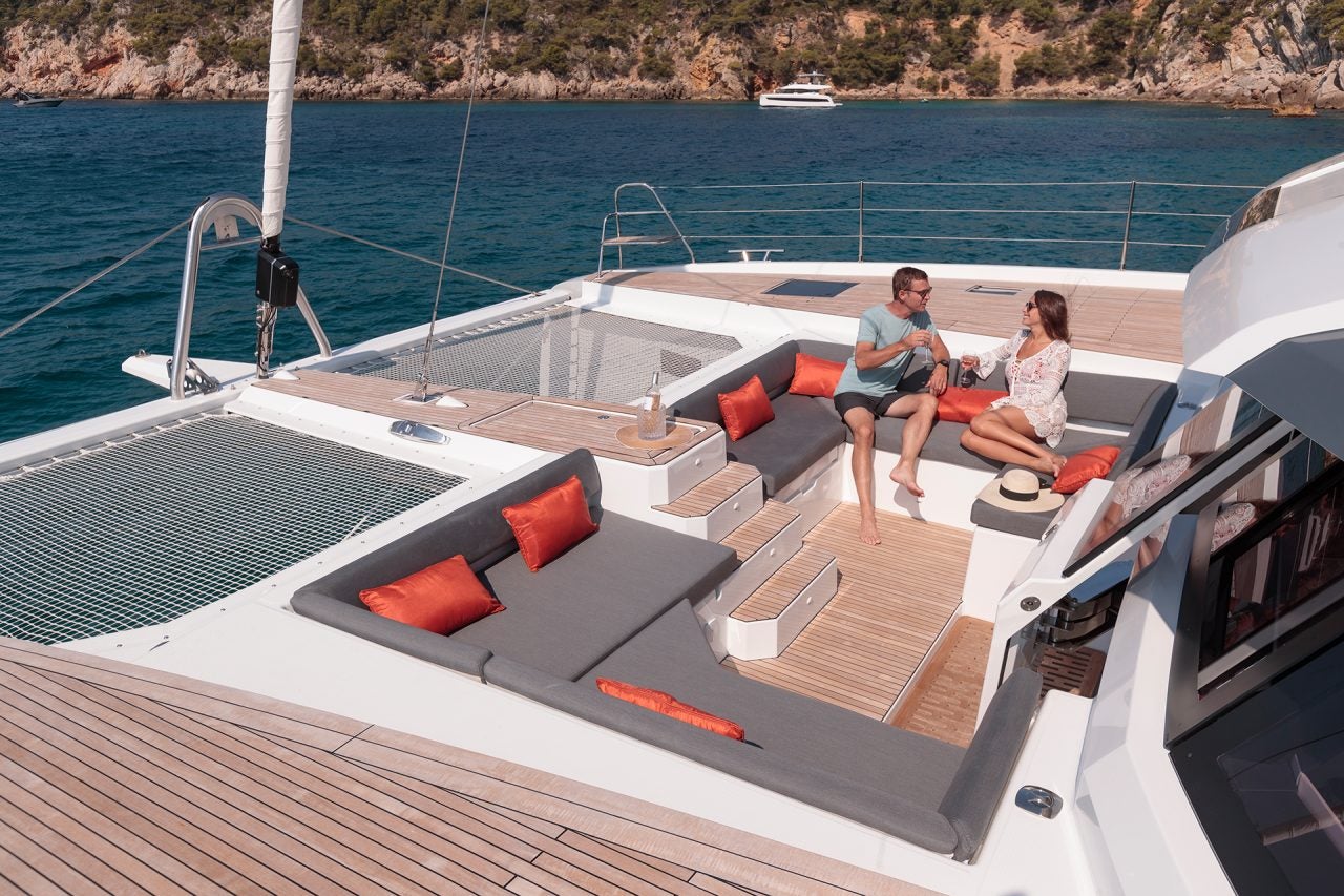 Coppia nel salone sul ponte anteriore dell'elegante catamarano Fountaine Pajot Samana 59