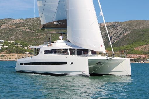 Catamarán de lujo Bali 5.4 navegando por unas aguas azules con una montaña al fondo