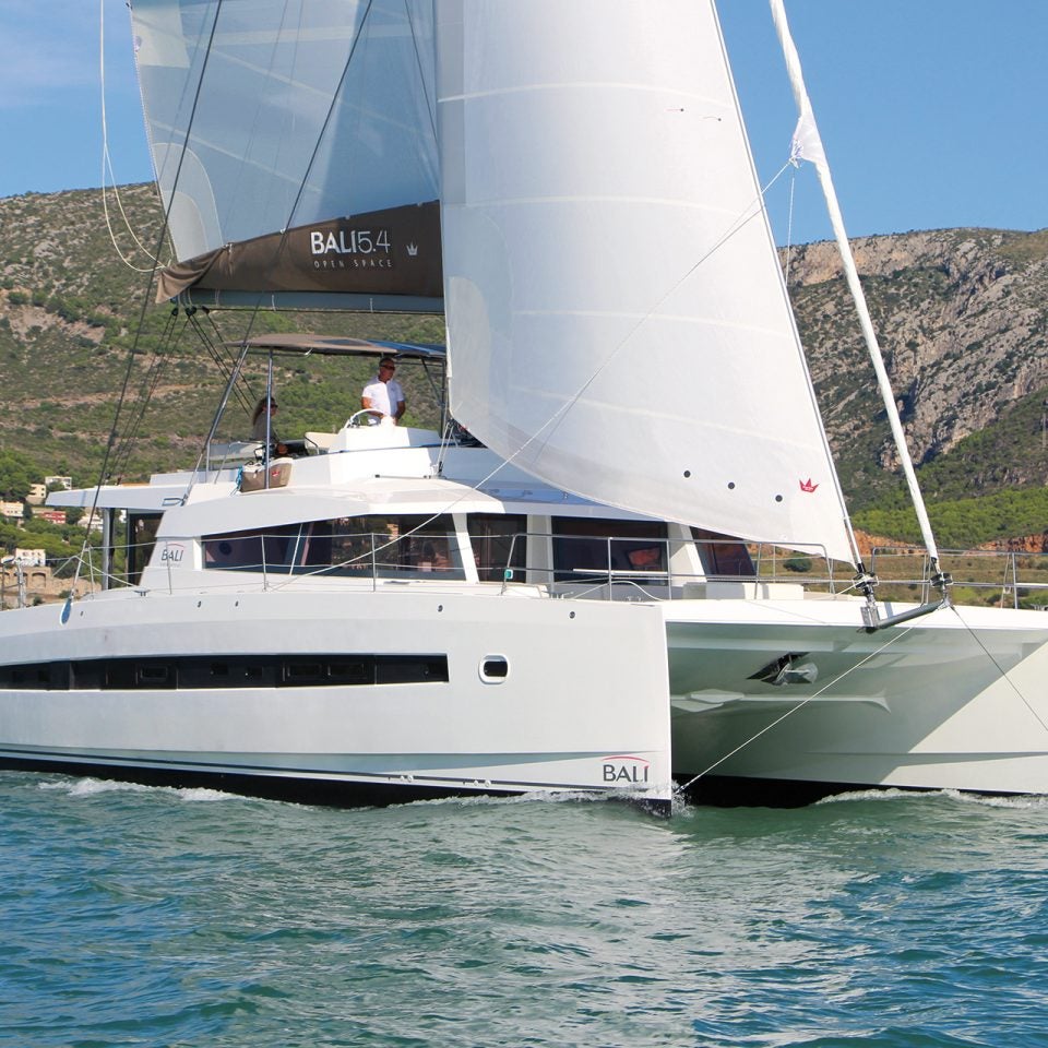 Catamarán de lujo Bali 5.4 navegando por unas aguas azules con una montaña al fondo