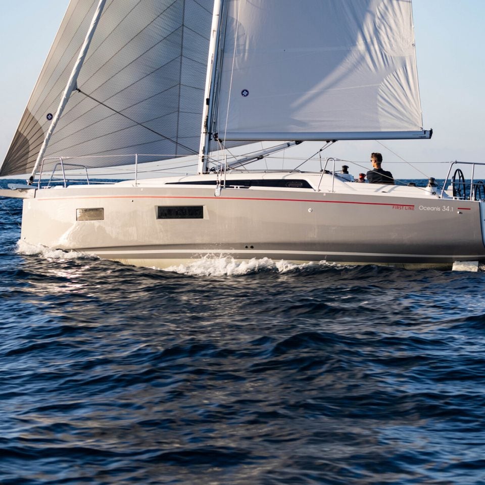 Barco Beneteau 34.1 con las velas izadas y un hombre al timón