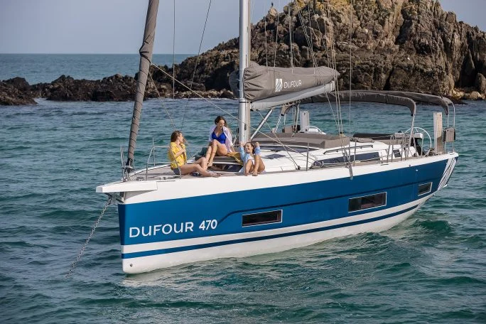 Dufour 470 sailboat at anchor with people on bow