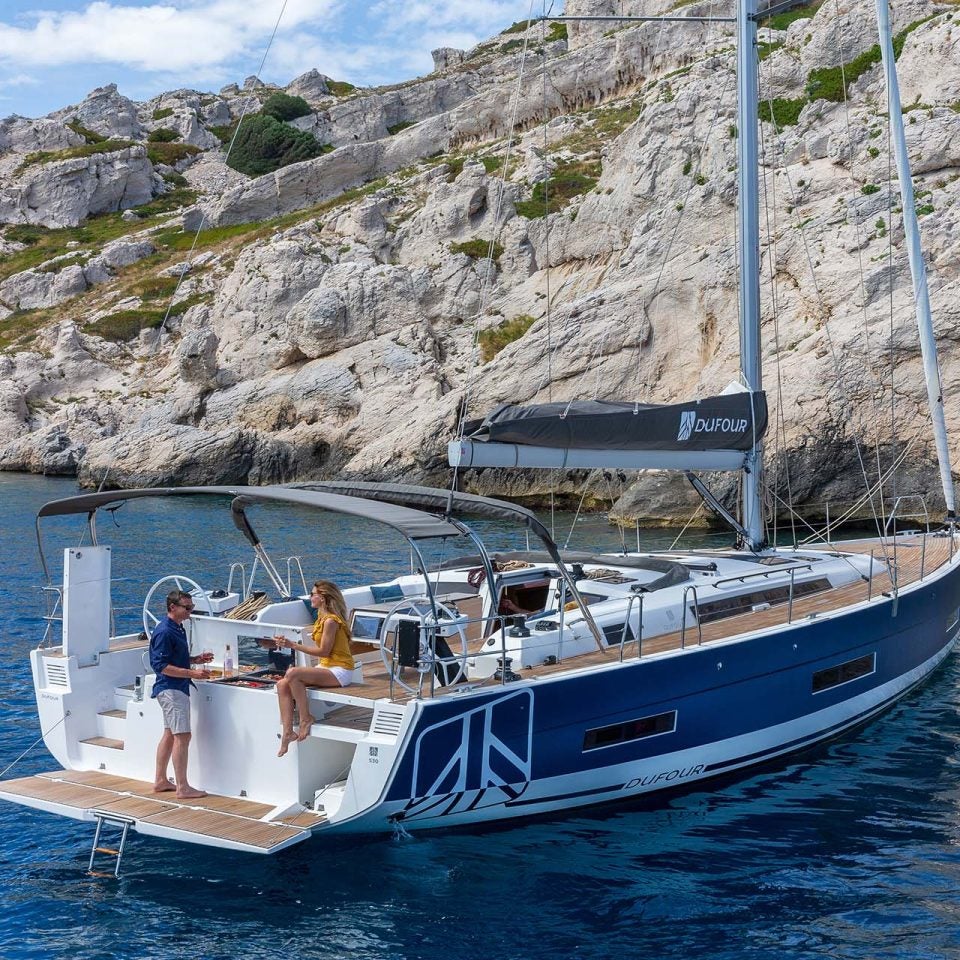 Das Elektro-Einrumpfboot Dufour 530 vor Anker, mit einem Paar, das am Spiegel grillt