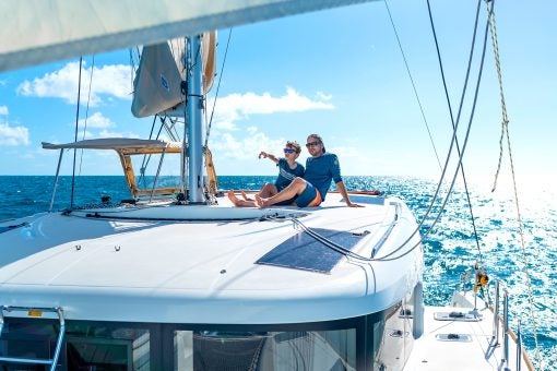 Man and boy lounging at top of a Dream yacht sailing catamaran