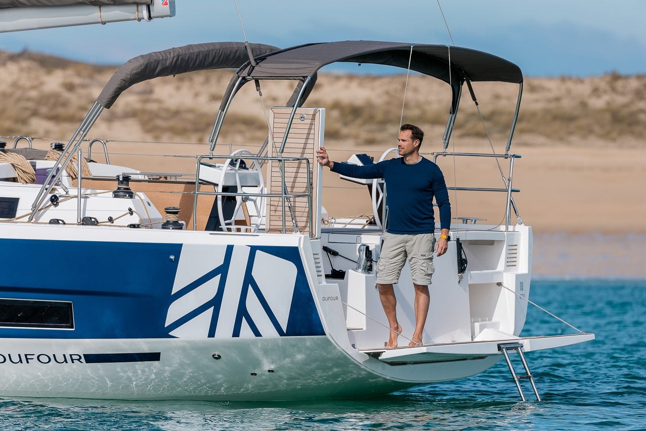 Homme sur la plateforme du tableau arrière du monocoque à voile électrique Dufour 470