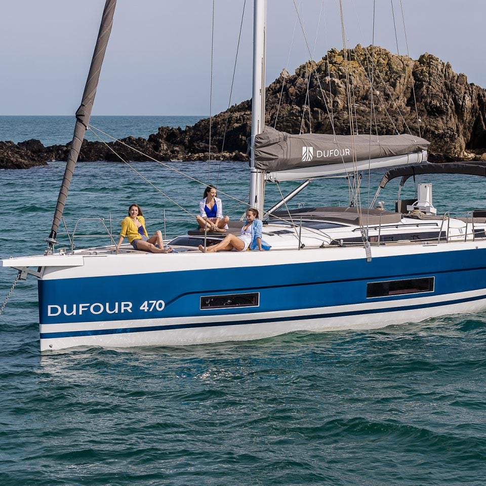 Das vor Anker liegende Elektro-Segelboot Dufour 470 mit mehreren Personen am Bug