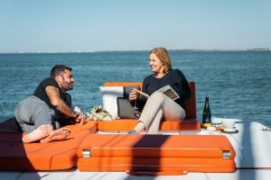 Couple dans la salon à sièges rembourrés à bord du catamaran à voile Excess 14