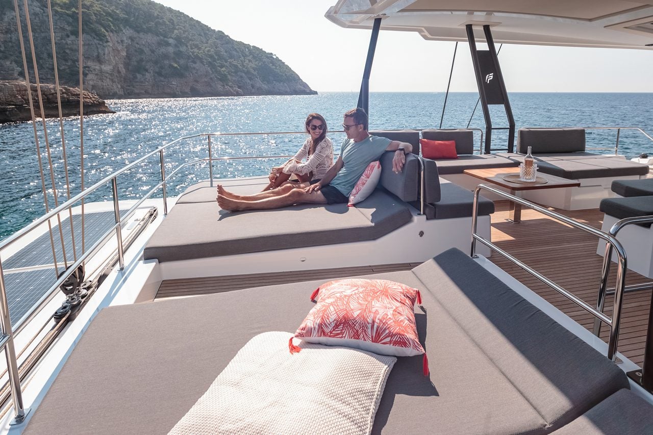 Couple sur l’espace de bain de soleil du flybridge du bateau de luxe Fountaine Pajot Samana 59