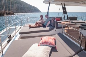 Ein Paar liegt auf der Flybridge der Luxusyacht Fountaine Pajot Samana 59 auf Sonnenliegen