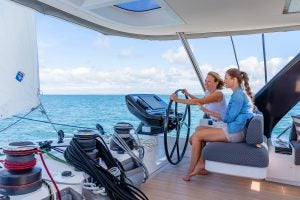 Dos mujeres sentadas al timón del catamarán a vela de lujo Lagoon 65