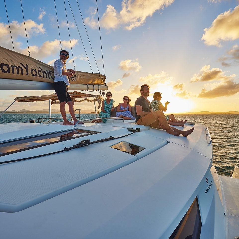 Grupo de propietarios de Dream Yacht sobre un catamarán a vela al atardecer