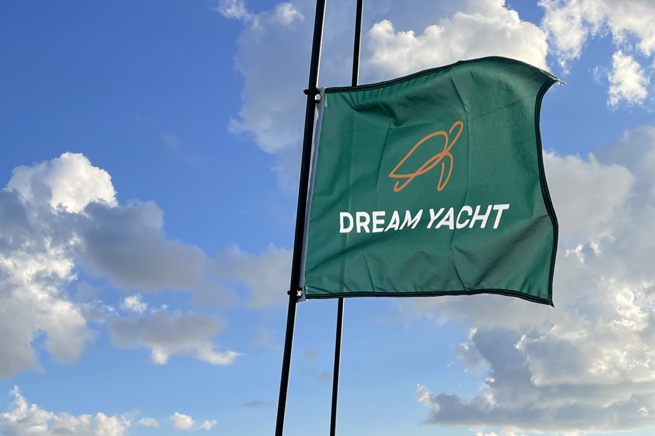 Bandera con la marca Dream Yacht ondeando bajo un cielo azul.