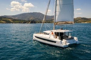 Catamarán Bali 4.2 a vela con unas exuberantes montañas repletas de vegetación al fondo