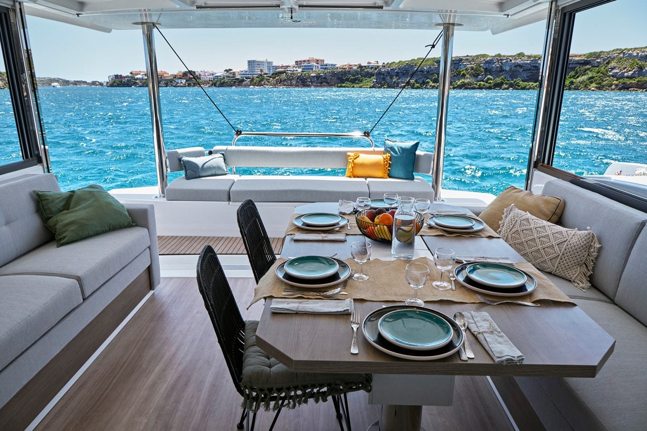 Salle à manger intérieure du bateau Bali 4.4 avec grande porte ouverte sur la mer