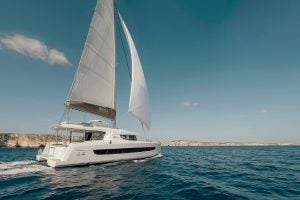 Catamarán Bali 4.4 navegando cerca de la costa rocosa de un acantilado