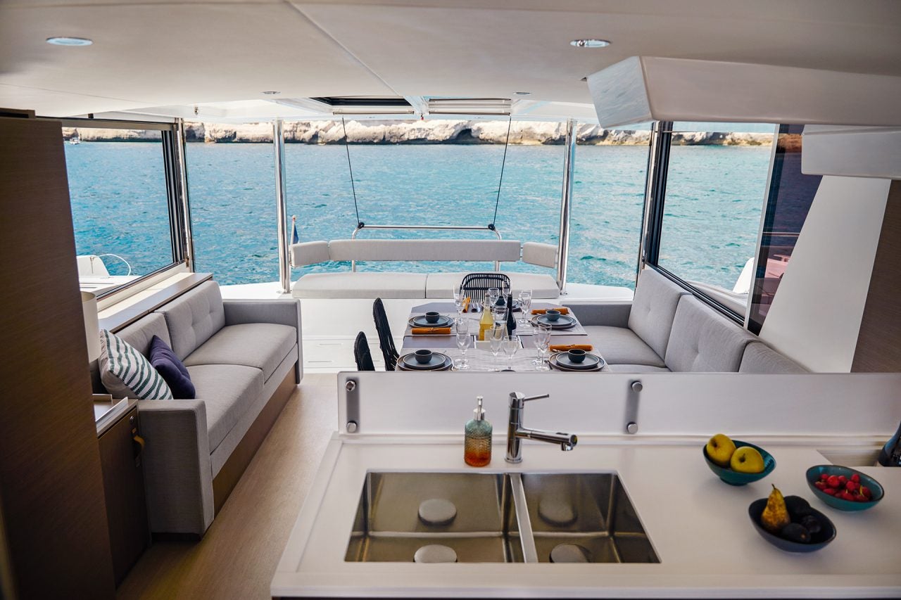 Salón del catamarán Bali 4.6 con una gran puerta y ventanas abiertas al exterior