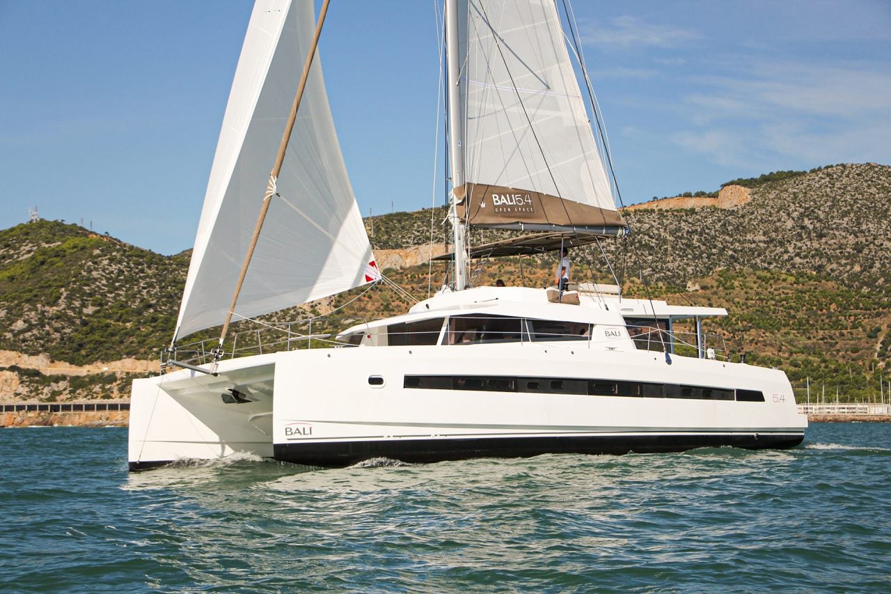 Catamarán Bali 5.4 navegando por unas aguas azules con una montaña al fondo