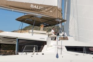 Uomo al timone dell'elegante catamarano a vela Bali 5.4