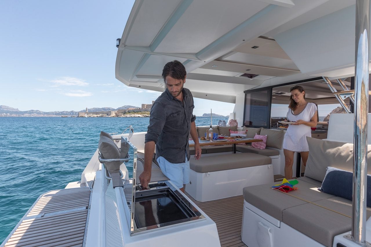 Un hombre usando una parrilla al aire libre en el catamarán Fountaine Pajot Astrea 42