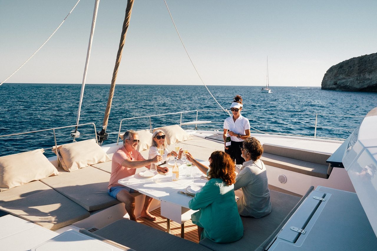 Mehrere Personen beim Abendessen am Außentisch des Vordecks an Bord von Bali 5.4