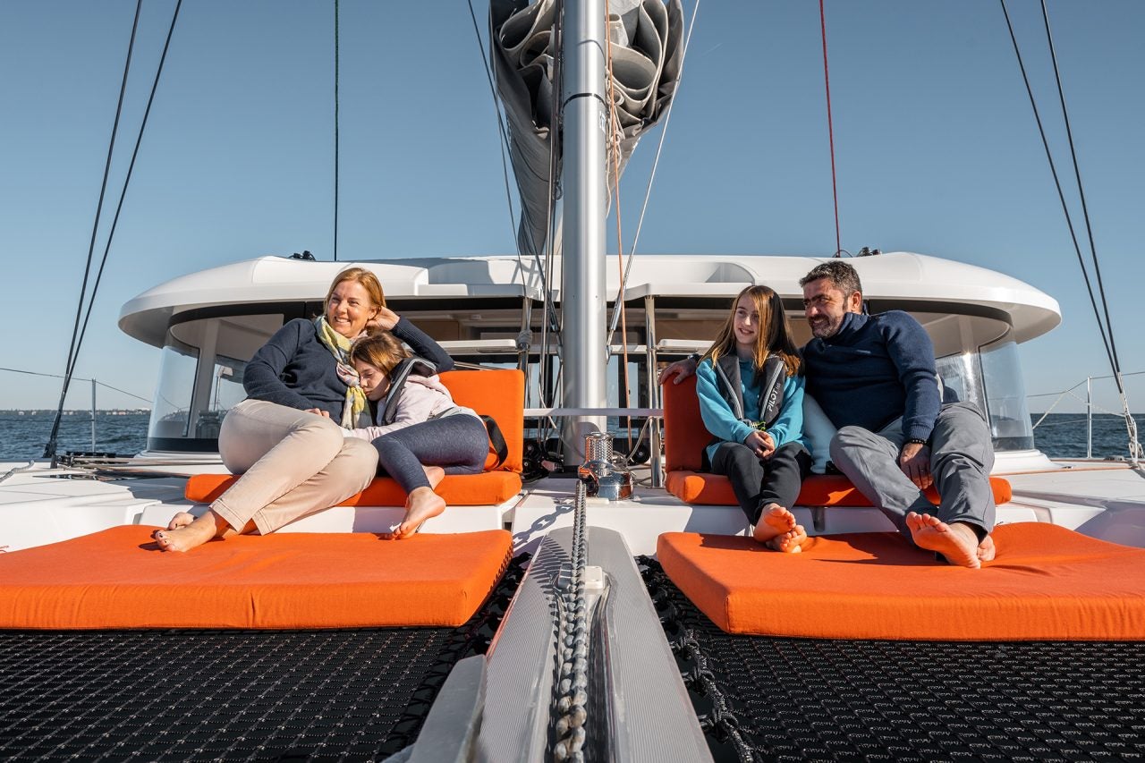 Una familia sentada en la cubierta delantera del catamarán a vela Excess 14