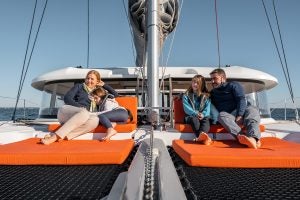 Famille assise sur le pont avant du catamaran à voile Excess 14