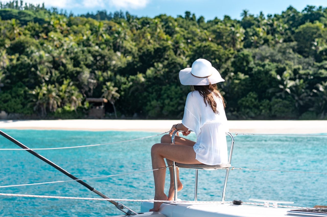 Huésped de Dream Yacht disfrutando de la vista de un destino de playa desde la proa de un catamarán