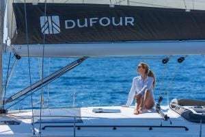 Femme assise sur le pont surélevé du bateau à voile électrique Dufour 530