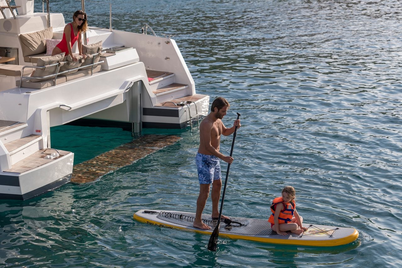 Coppia che utilizza la plancetta del catamarano Astrea 42 per il paddleboarding