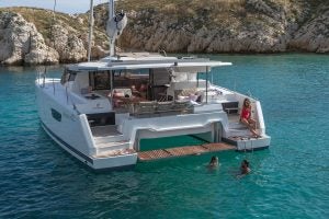 Catamarán eléctrico inteligente Astrea 42 fondeando cerca de una costa rocosa