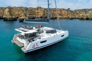 Der Segelkatamaran Fountaine Pajot Elba 45 liegt in der Nähe von Klippen vor Anker