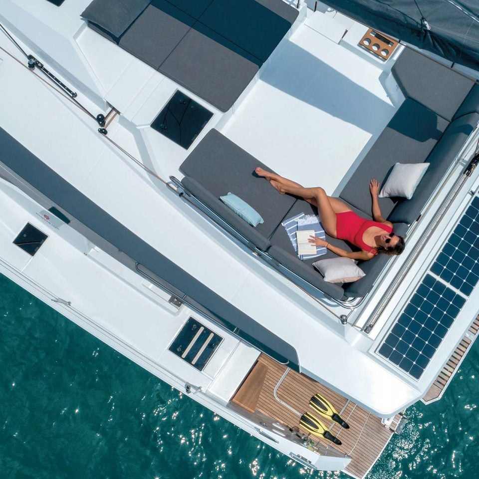 Vista superior de una mujer en la zona de estar del puente volante del catamarán eléctrico Elba 45