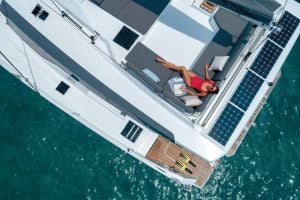 Vue de dessus d’une femme se prélassant sur le flybridge du catamaran à voile Elba 45