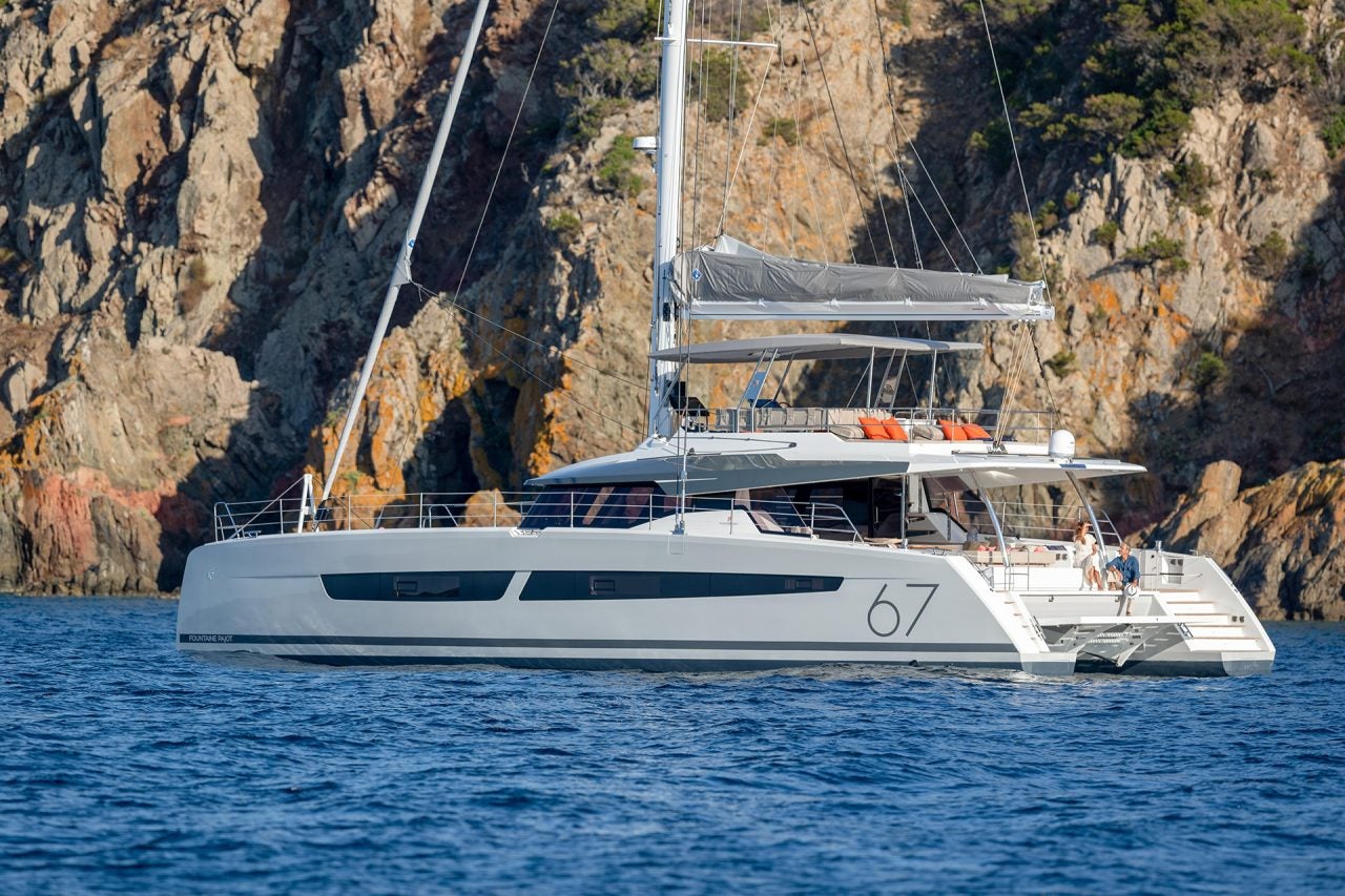 Catamarán Fountaine Pajot Alegria 67 anclado cerca de una costa escarpada