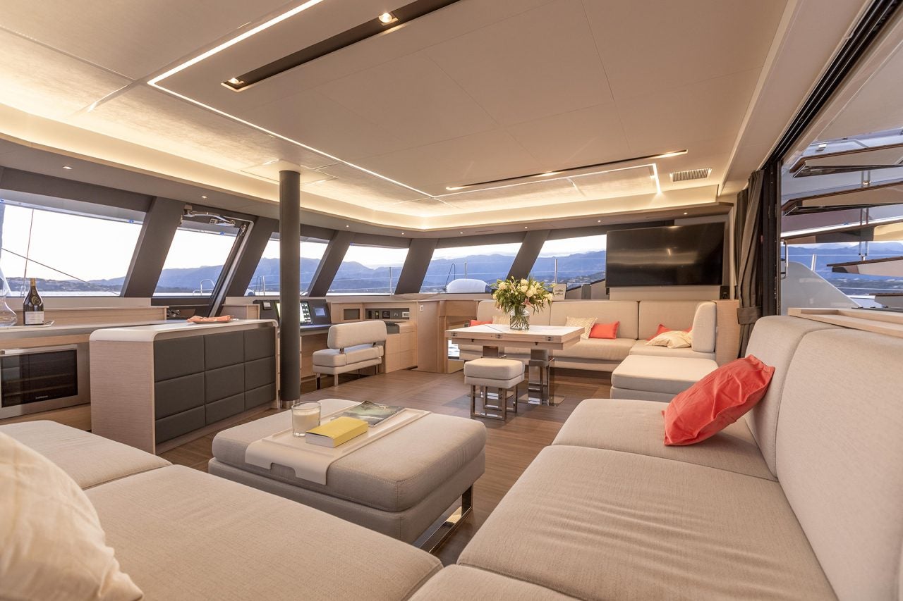 Un puente de mando con mesa de comedor a bordo del catamarán Fountaine Pajot 67