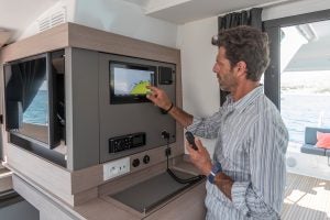 Hombre usando la electrónica interior del catamarán a vela Isla 40