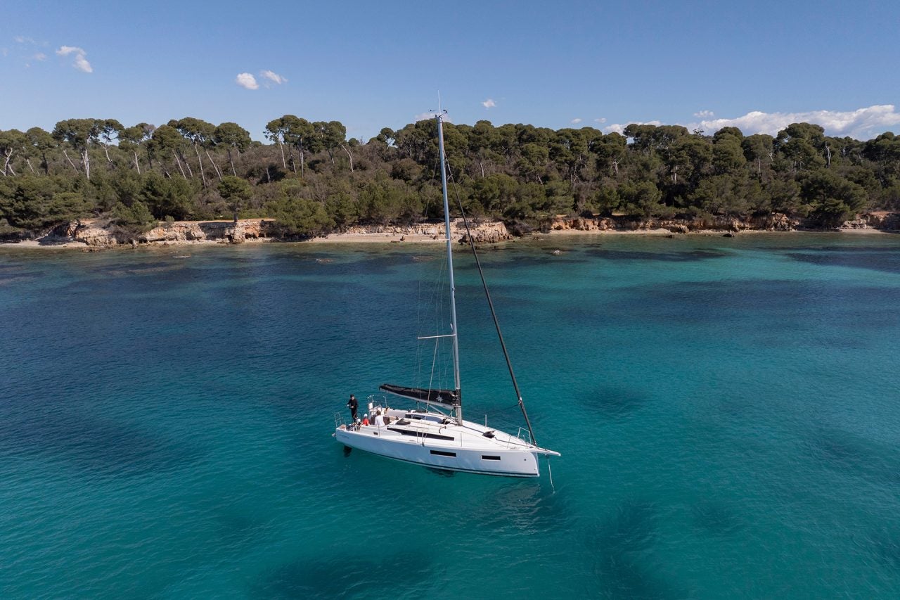 Das Einrumpfsegelboot Jeanneau Sun Odyssey 350 liegt in Küstennähe vor Anker