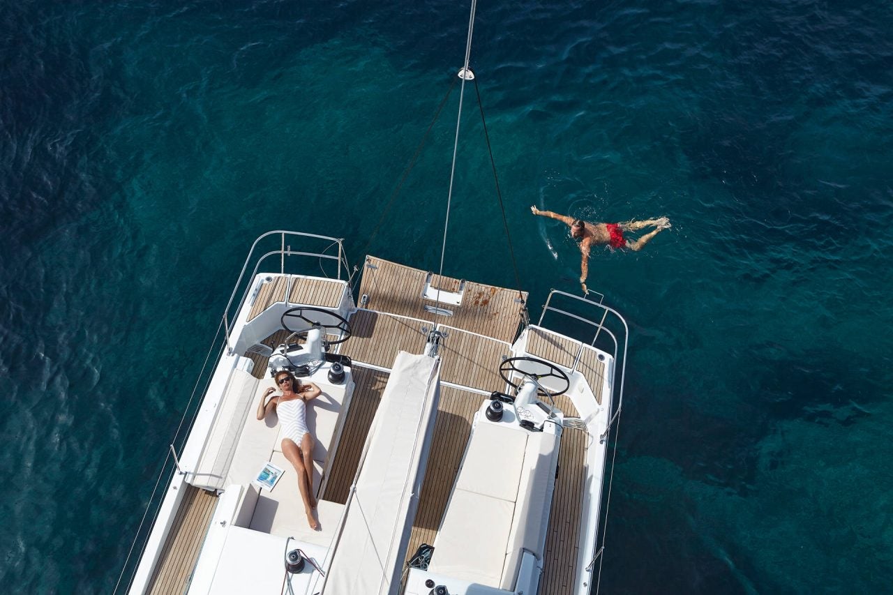 Una mujer nadando junto a la plataforma del monocasco Sun Odyssey 490