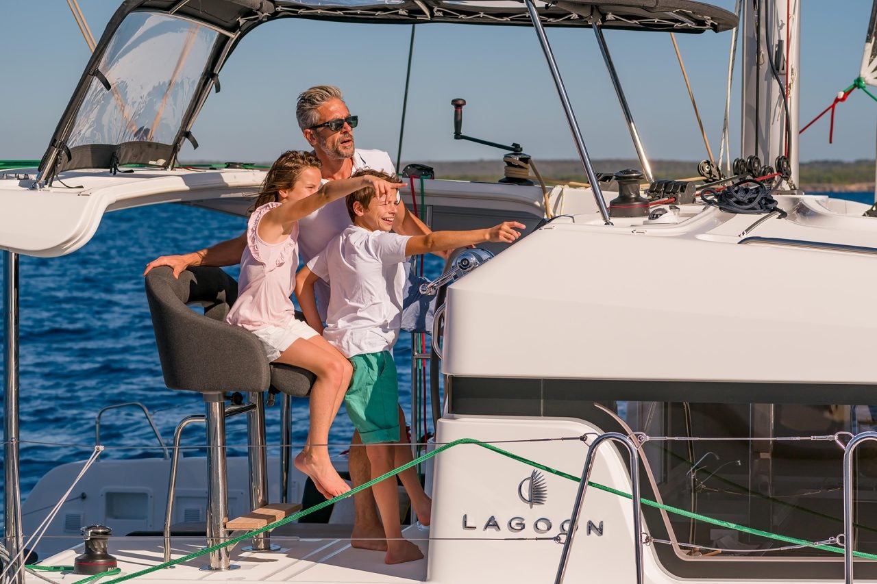 Homme et enfants à la barre du voilier Lagoon 40