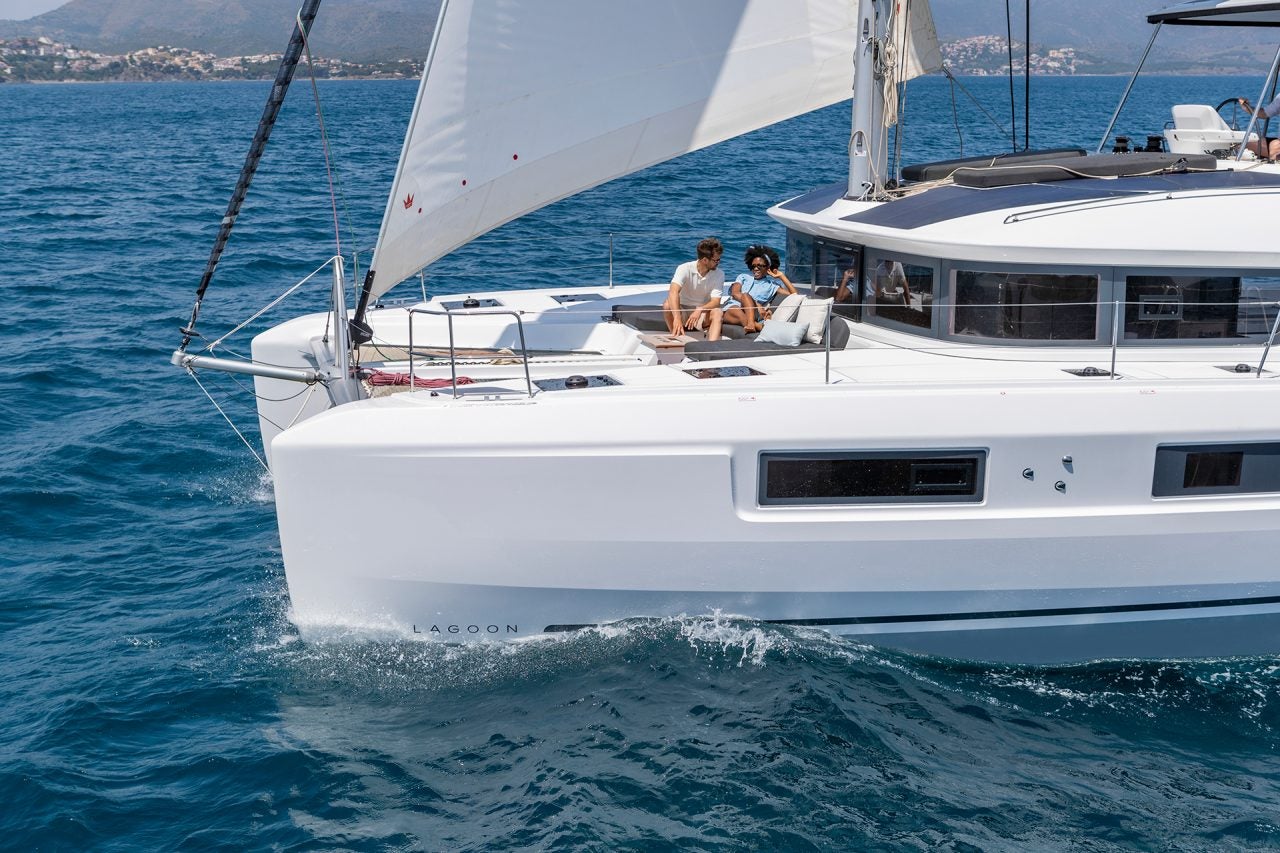 Catamaran de luxe Lagoon 51 naviguant avec un couple sur le pont avant