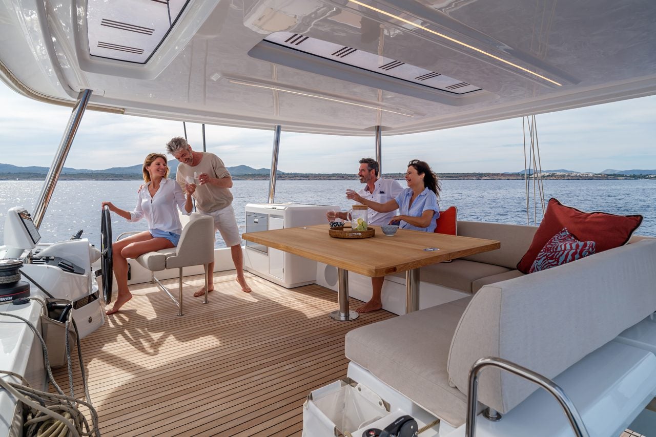 Unos amigos disfrutando del amplio puente aéreo del catamarán a vela Lagoon 55