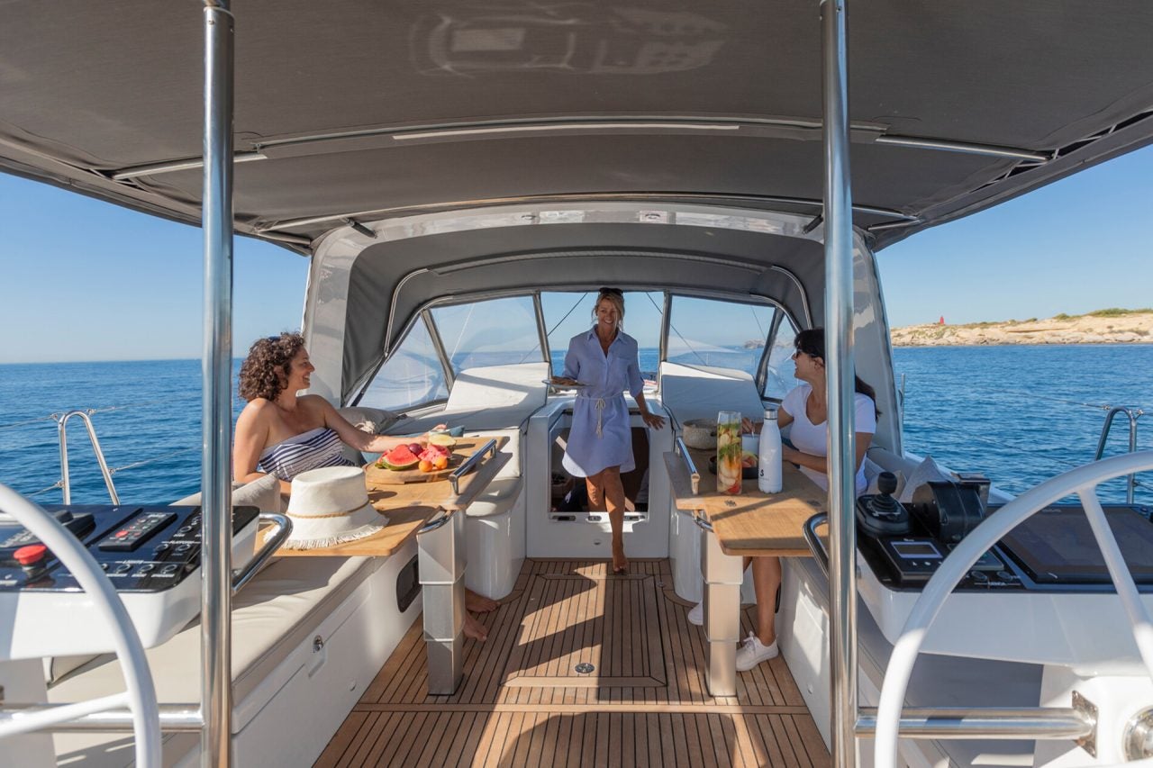 Unas personas en la mesa de comedor del monocasco de lujo Beneteau Yacht 54