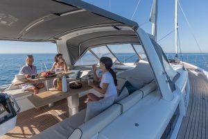 Unas personas en la mesa de comedor del monocasco Beneteau Oceanis Yacht 54