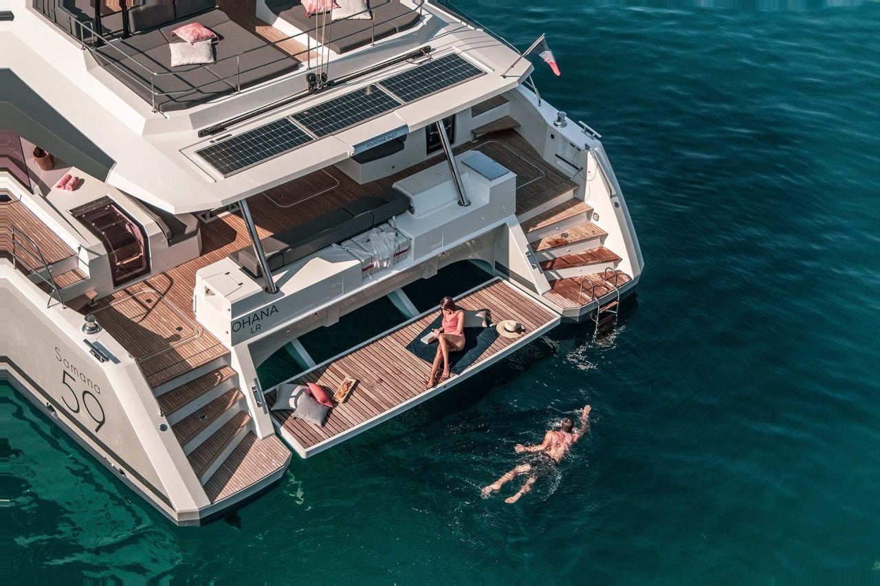 Una pareja disfrutando de la plataforma de baño del catamarán Samana 59