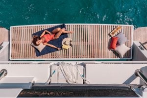 Donna che prende il sole sulla plancetta dell'elegante catamarano Fountaine Pajot 67