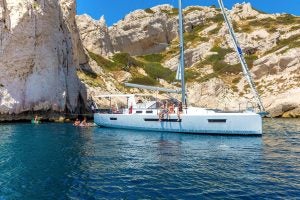 Das Segelboot Sun Loft 47 liegt vor Anker, mehrere Personen schwimmen in der Nähe