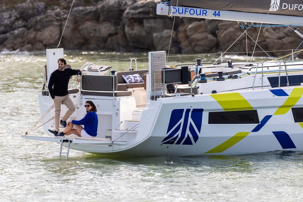 Couple assis sur la plateforme du tableau arrière du voilier Dufour 44