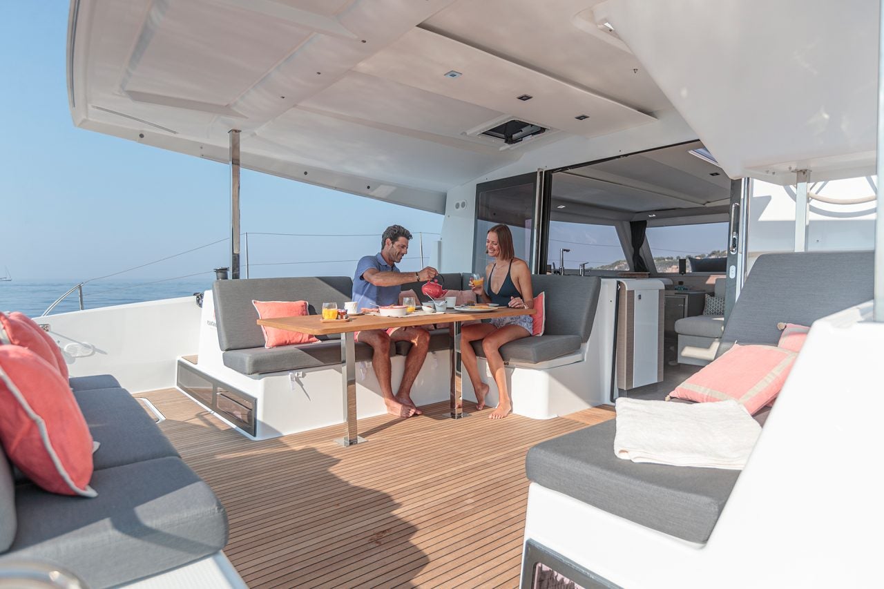 Una pareja comiendo en la mesa del puente de mando del catamarán a vela Isla 40