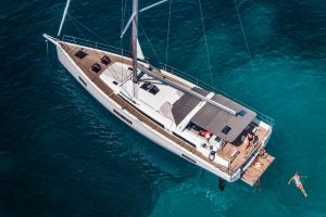 Eine Frau schwimmt in der Nähe des Einrumpfsegelboots Oceanis Yacht 54